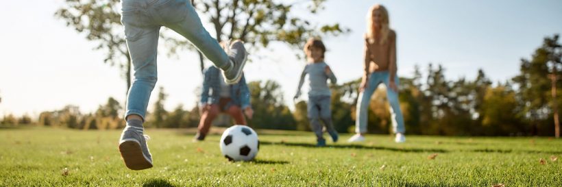 family playing soccer in the park