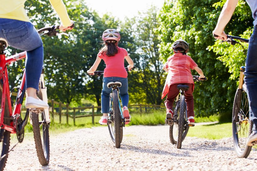 family of 4 riding bikes on trail